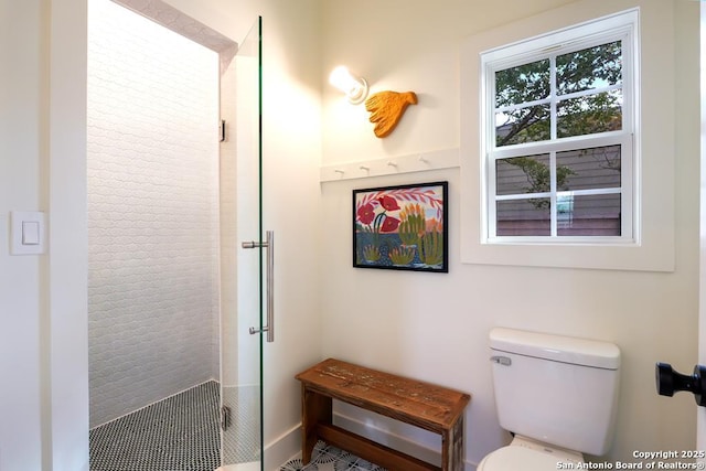 bathroom with a shower with shower door and toilet