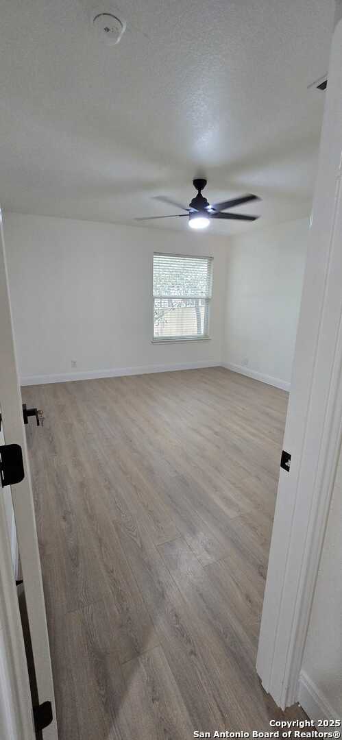 spare room with ceiling fan, a textured ceiling, and light wood-type flooring