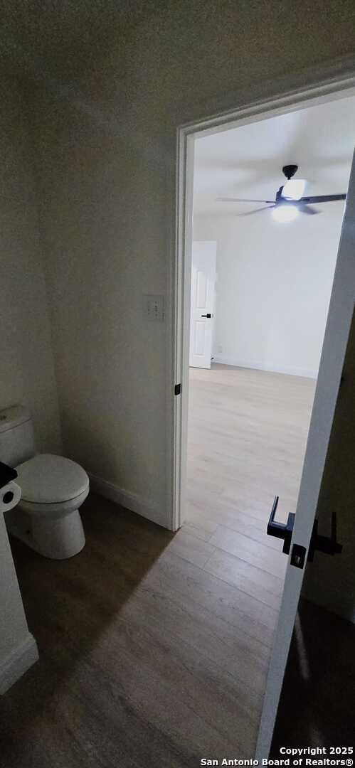 bathroom featuring ceiling fan, wood-type flooring, and toilet