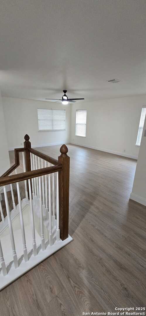 staircase with ceiling fan and wood-type flooring