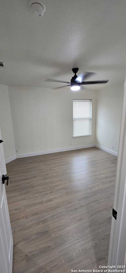 unfurnished room featuring a textured ceiling, ceiling fan, and light wood-type flooring