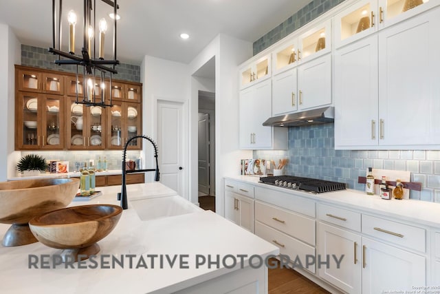 kitchen with white cabinetry, decorative light fixtures, and stainless steel gas stovetop