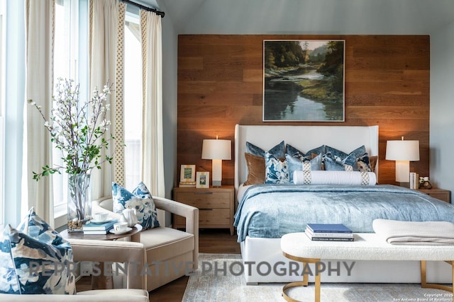 bedroom featuring wooden walls, hardwood / wood-style floors, and multiple windows