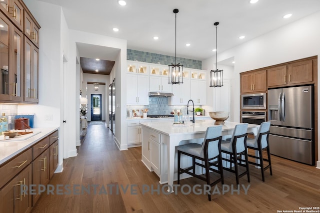 kitchen featuring white cabinetry, a kitchen island with sink, stainless steel appliances, and a kitchen bar