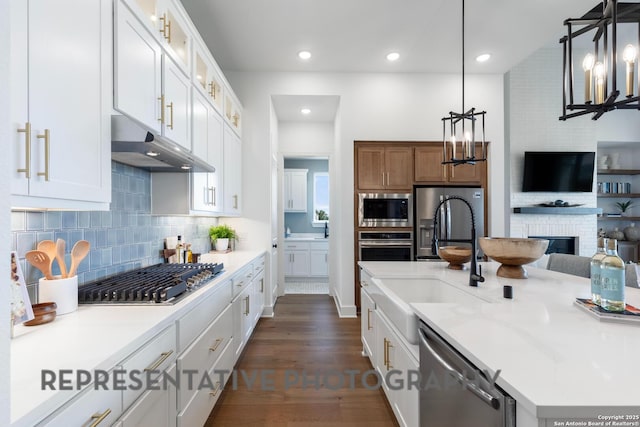 kitchen featuring stainless steel appliances, light stone countertops, hanging light fixtures, and white cabinets