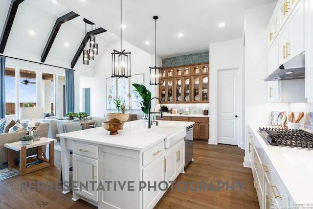 kitchen featuring appliances with stainless steel finishes, sink, vaulted ceiling with beams, white cabinets, and a center island with sink