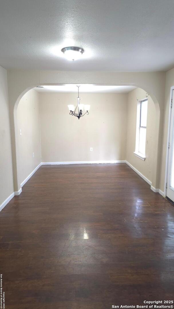 unfurnished dining area with dark hardwood / wood-style flooring, a textured ceiling, and a chandelier