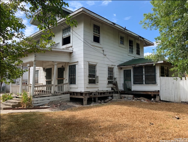 back of property featuring a lawn and a porch