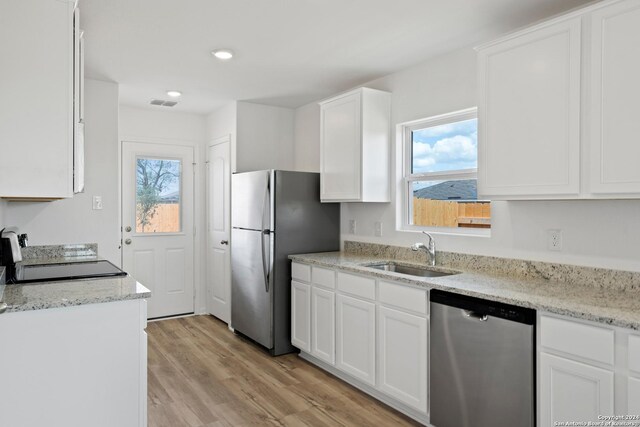 11506 Bald Eagle Hts, San Antonio, TX 78223 - kitchen featuring white cabinetry, sink, stainless steel appliances, a healthy amount of sunlight, and light hardwood / wood-style flooring