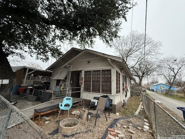 back of property with central AC and a sunroom