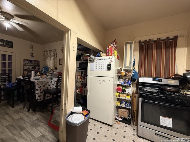 kitchen with white refrigerator, stainless steel range with gas cooktop, and ceiling fan