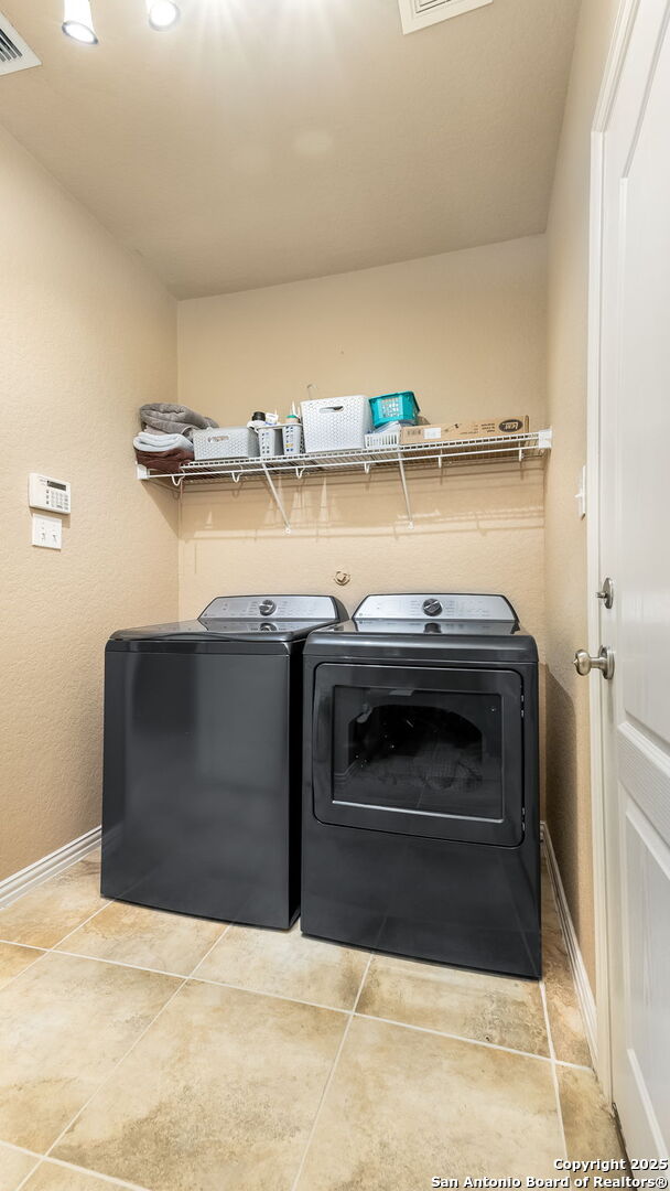 clothes washing area featuring separate washer and dryer and light tile patterned floors