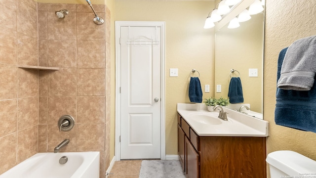 full bathroom featuring tiled shower / bath, vanity, toilet, and tile patterned floors