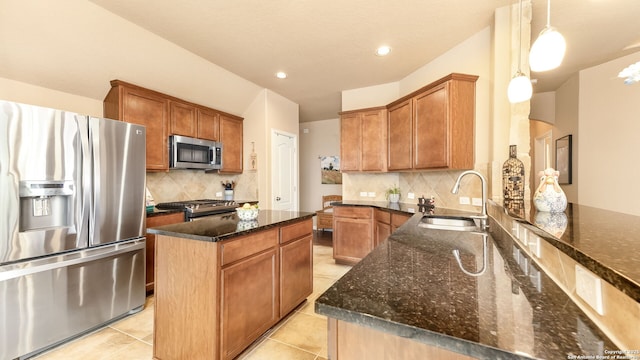 kitchen with sink, decorative light fixtures, dark stone countertops, a kitchen island, and stainless steel appliances