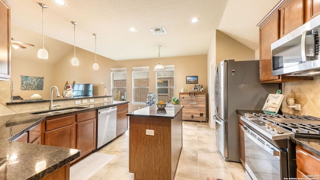 kitchen featuring a kitchen island, decorative light fixtures, sink, backsplash, and stainless steel appliances