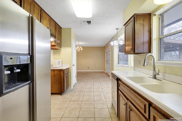 kitchen with appliances with stainless steel finishes, decorative light fixtures, sink, a chandelier, and light tile patterned floors