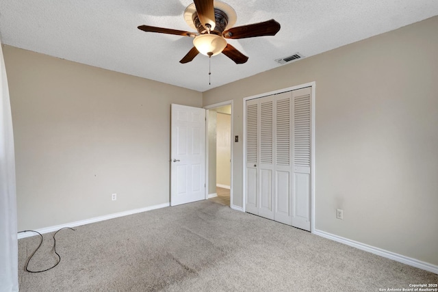 unfurnished bedroom with ceiling fan, carpet floors, a textured ceiling, and a closet