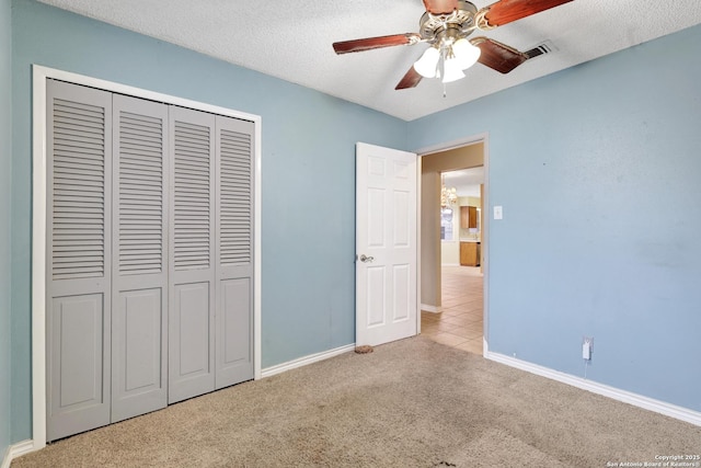 unfurnished bedroom featuring ceiling fan, light colored carpet, a closet, and a textured ceiling