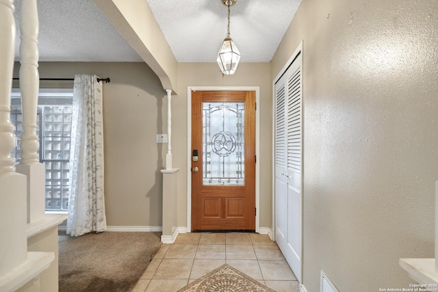 foyer entrance with a textured ceiling and light tile patterned floors