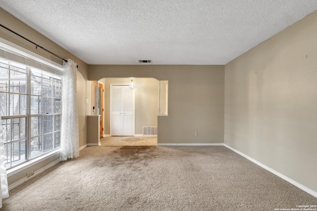 carpeted empty room featuring a textured ceiling