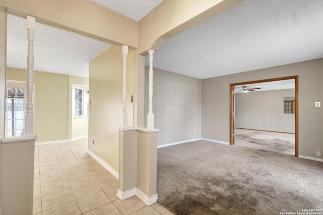 tiled spare room with ceiling fan, decorative columns, and a textured ceiling