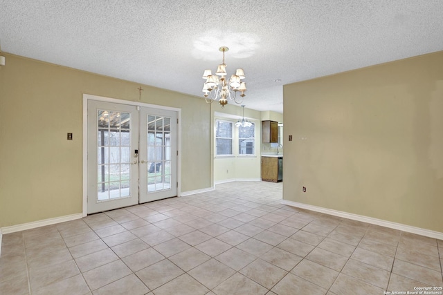 tiled empty room with an inviting chandelier, french doors, and a textured ceiling