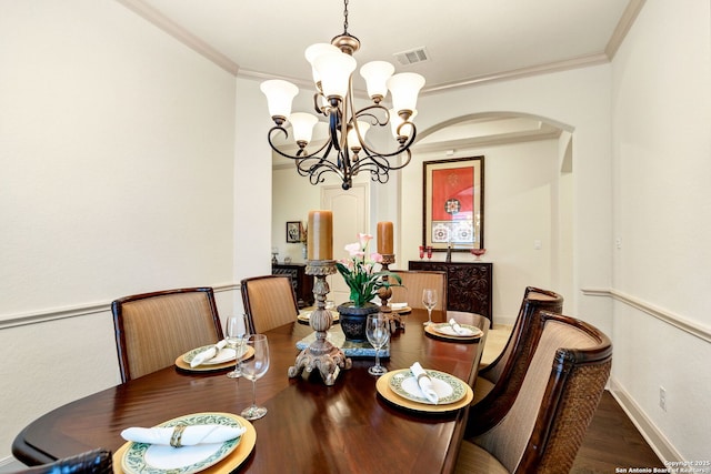 dining space featuring crown molding, dark wood-type flooring, and a chandelier