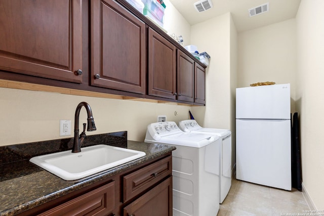 clothes washing area with light tile patterned flooring, cabinets, sink, and washing machine and dryer