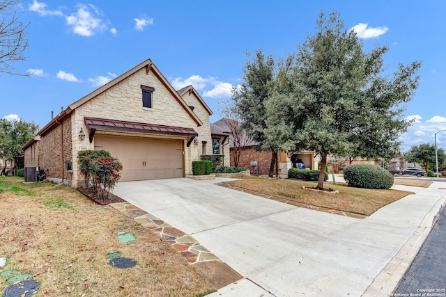 view of front of home featuring a garage, a front yard, and central air condition unit