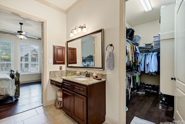 bathroom featuring vanity, hardwood / wood-style flooring, ornamental molding, and ceiling fan