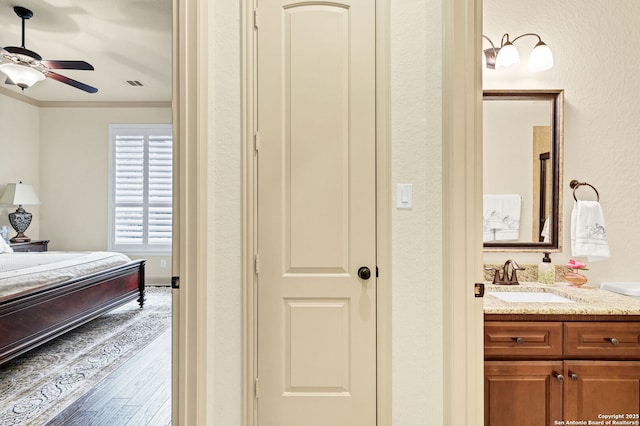 bedroom featuring hardwood / wood-style flooring, ornamental molding, and sink