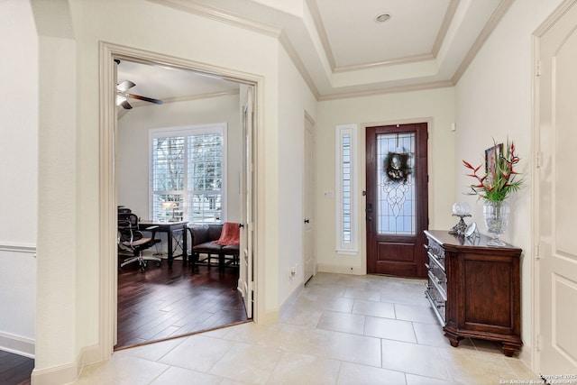 tiled entryway with crown molding and a tray ceiling