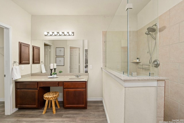 bathroom featuring a tile shower, hardwood / wood-style floors, and vanity