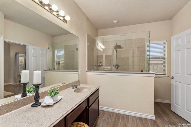 bathroom with wood-type flooring, vanity, and a tile shower