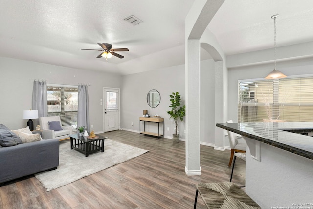 living room with dark wood-type flooring, ceiling fan, and a textured ceiling