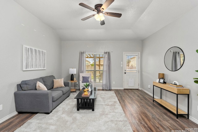 living room with dark wood-type flooring, ceiling fan, and a textured ceiling