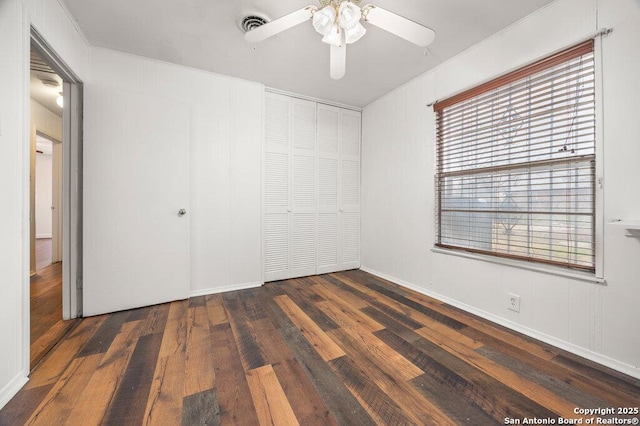 unfurnished bedroom featuring ceiling fan, ornamental molding, dark hardwood / wood-style flooring, and a closet