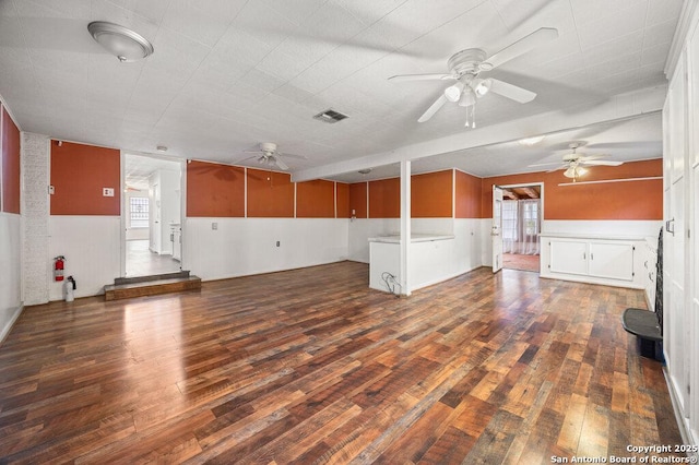 unfurnished living room featuring dark wood-type flooring and ceiling fan