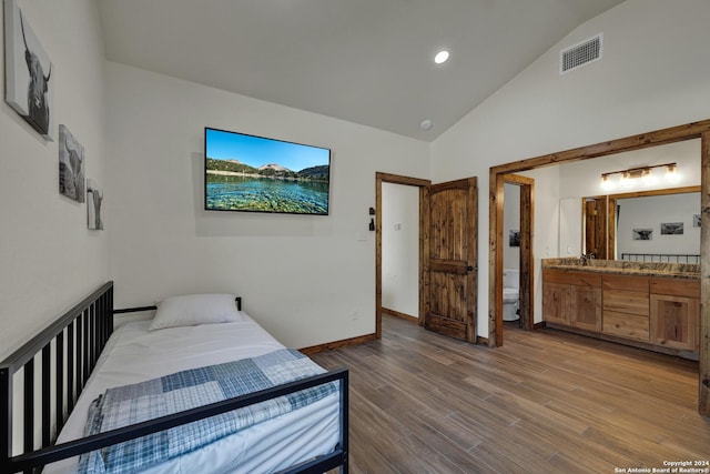 bedroom with high vaulted ceiling, connected bathroom, and hardwood / wood-style floors