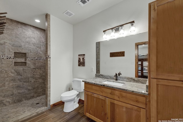 bathroom featuring tiled shower, vanity, and toilet