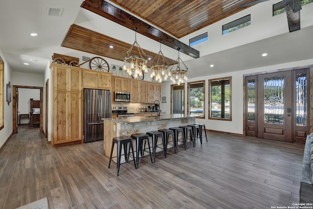 kitchen featuring stainless steel appliances, an island with sink, dark hardwood / wood-style floors, and decorative light fixtures