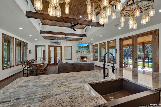 kitchen featuring sink, light stone countertops, french doors, and vaulted ceiling with beams