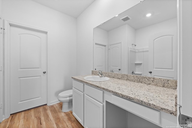 bathroom featuring vanity, toilet, wood-type flooring, and a shower