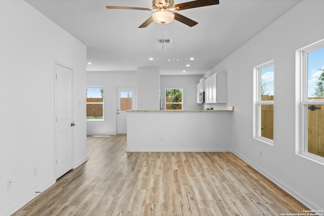 interior space featuring ceiling fan, light hardwood / wood-style floors, kitchen peninsula, and white cabinets