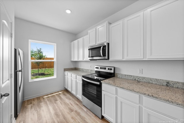 kitchen featuring white cabinetry, appliances with stainless steel finishes, light stone countertops, and light hardwood / wood-style floors