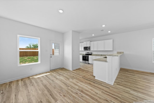 kitchen featuring white cabinetry, appliances with stainless steel finishes, light stone counters, and light hardwood / wood-style floors