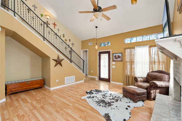 living room featuring a towering ceiling, light hardwood / wood-style floors, and ceiling fan