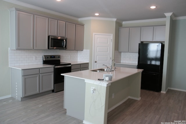 kitchen with an island with sink, sink, gray cabinetry, stainless steel appliances, and light hardwood / wood-style flooring