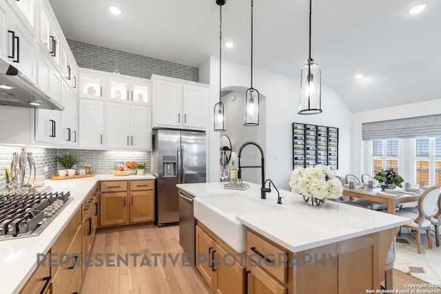 kitchen with appliances with stainless steel finishes, decorative light fixtures, sink, white cabinets, and a center island with sink