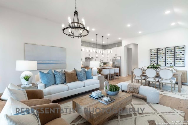 living room with sink, an inviting chandelier, and light hardwood / wood-style floors